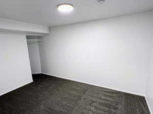 Unfurnished bedroom with dark colored carpet and a closet