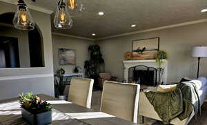 Dining space featuring ornamental molding, a textured ceiling, and a brick fireplace