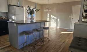 Kitchen featuring dishwasher, a kitchen breakfast bar, dark hardwood / wood-style flooring, white fridge, and a chandelier