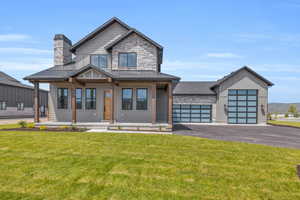 View of front of home featuring covered porch, a front yard, and a garage