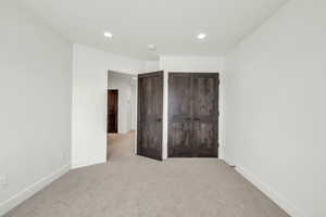 Unfurnished bedroom featuring light carpet and a closet