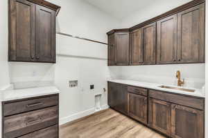 Washroom featuring cabinets, sink, hookup for a washing machine, light wood-type flooring, and hookup for an electric dryer