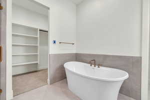 Bathroom featuring a washtub, tile walls, and tile patterned flooring