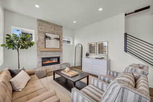 Living room with a stone fireplace, light hardwood / wood-style flooring, and a healthy amount of sunlight