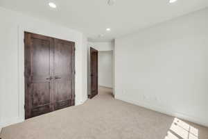 Unfurnished bedroom with light colored carpet and a closet