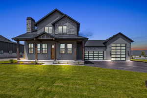 View of front of home featuring a porch, a garage, and a lawn