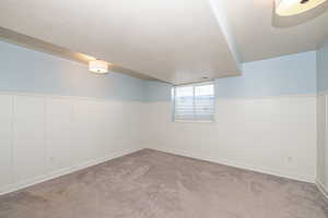 Basement with light carpet and a textured ceiling