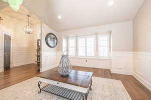 Sitting room with dark hardwood / wood-style floors, lofted ceiling, and a notable chandelier