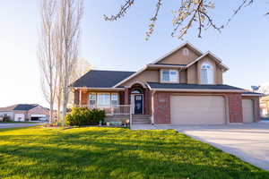 View of front of home featuring covered porch, a garage, and a front lawn