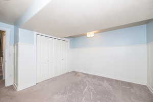 Basement featuring light carpet and a textured ceiling