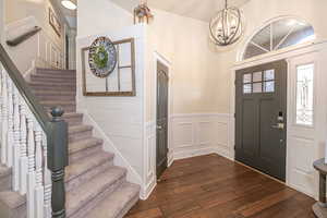 Entrance foyer with dark wood-type flooring and an inviting chandelier