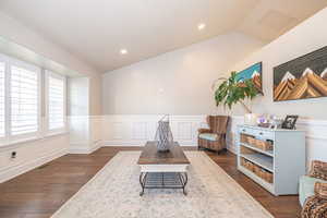 Sitting room with lofted ceiling and dark wood-type flooring