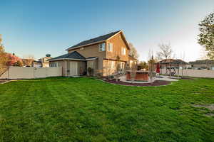 Back of house featuring a yard, a hot tub, and a patio area