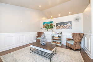 Sitting room with dark hardwood / wood-style floors and lofted ceiling