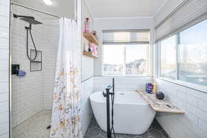 Bathroom featuring shower with separate bathtub, tile patterned floors, and tile walls