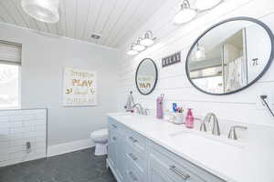 Bathroom featuring tile patterned floors, toilet, wooden walls, vanity, and wood ceiling