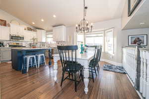 Dining area with dark hardwood / wood-style floors, a healthy amount of sunlight, lofted ceiling, and an inviting chandelier