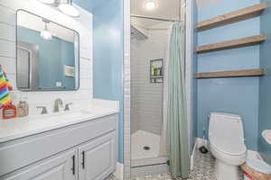 Bathroom featuring tile patterned flooring, vanity, toilet, and walk in shower