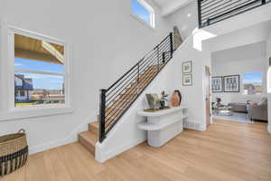 Stairs with beamed ceiling, hardwood / wood-style floors, plenty of natural light, and a high ceiling