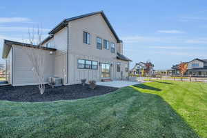 Back of property with central AC unit, a patio area, and a yard