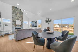 Dining area with a fireplace, high vaulted ceiling, and light hardwood / wood-style flooring