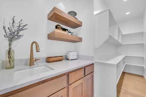 Interior space featuring light stone counters, sink, and light wood-type flooring