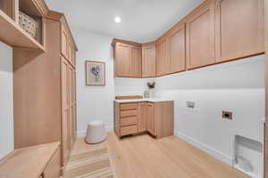 Laundry room featuring electric dryer hookup, cabinets, hookup for a washing machine, and light hardwood / wood-style floors