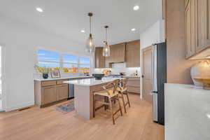 Kitchen with a center island, stainless steel appliances, a kitchen breakfast bar, light hardwood / wood-style floors, and custom range hood