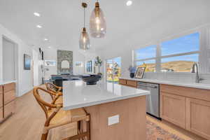 Kitchen with a kitchen breakfast bar, light wood-type flooring, a mountain view, decorative light fixtures, and dishwasher