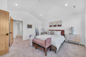 Bedroom featuring light carpet and vaulted ceiling