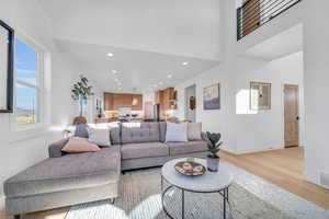 Living room with a towering ceiling and light hardwood / wood-style flooring