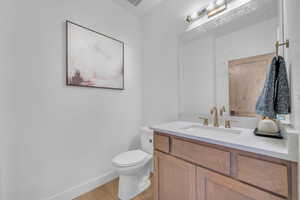 Bathroom with vanity, toilet, and wood-type flooring