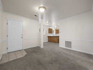 Unfurnished living room featuring crown molding and light carpet