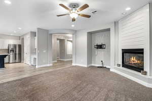 Unfurnished living room with a fireplace, light wood-type flooring, and ceiling fan