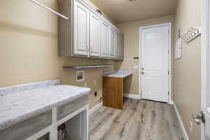 Laundry room with electric dryer hookup, cabinets, light wood-type flooring, and hookup for a washing machine