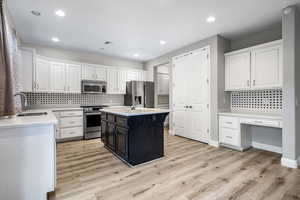 Kitchen featuring a center island, white cabinets, stainless steel appliances, and light wood-type flooring