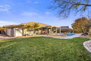 Back of house featuring a lawn, a patio area, and a pool with hot tub