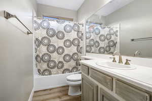 Full bathroom featuring hardwood / wood-style floors, vanity,  shower combination, and toilet