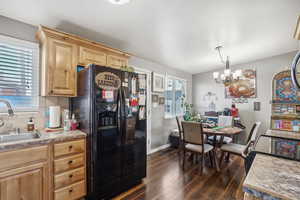 Kitchen featuring sink, tasteful backsplash, black fridge, dark hardwood / wood-style floors, and a chandelier