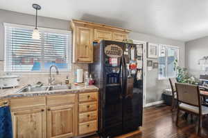 Kitchen featuring dark hardwood / wood-style flooring, backsplash, black fridge with ice dispenser, sink, and pendant lighting