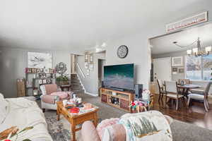 Living room with dark hardwood / wood-style flooring and a notable chandelier