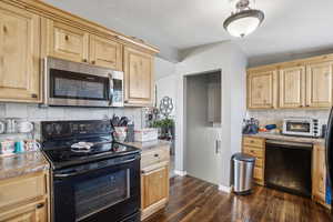 Kitchen featuring decorative backsplash, light brown cabinets, dark hardwood / wood-style floors, and black appliances