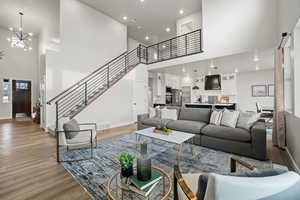 Living room with a notable chandelier, a towering ceiling, and light hardwood / wood-style flooring