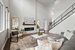 Living room with a towering ceiling and hardwood / wood-style flooring