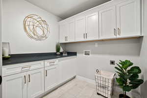 Clothes washing area featuring electric dryer hookup, light tile patterned floors, cabinets, and washer hookup