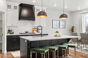 Kitchen with pendant lighting, premium range hood, and white cabinetry