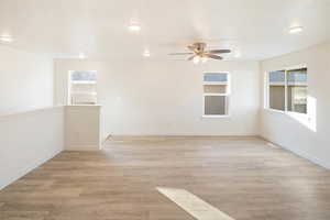 Empty room featuring ceiling fan, light hardwood / wood-style floors, and a textured ceiling