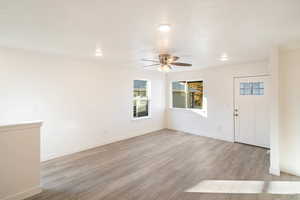 Foyer entrance featuring ceiling fan, light wood-type flooring, and a textured ceiling