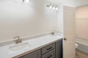 Bathroom featuring a bath, vanity, hardwood / wood-style flooring, and toilet