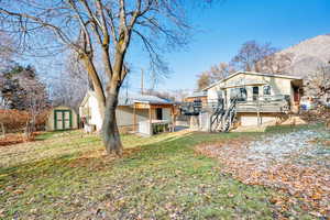 View of yard featuring a deck with mountain view and a storage shed